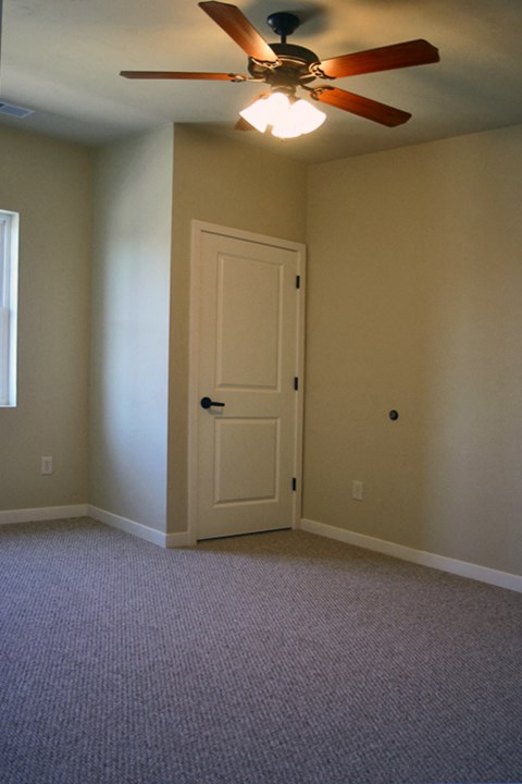 an empty living room with a ceiling fan and a door