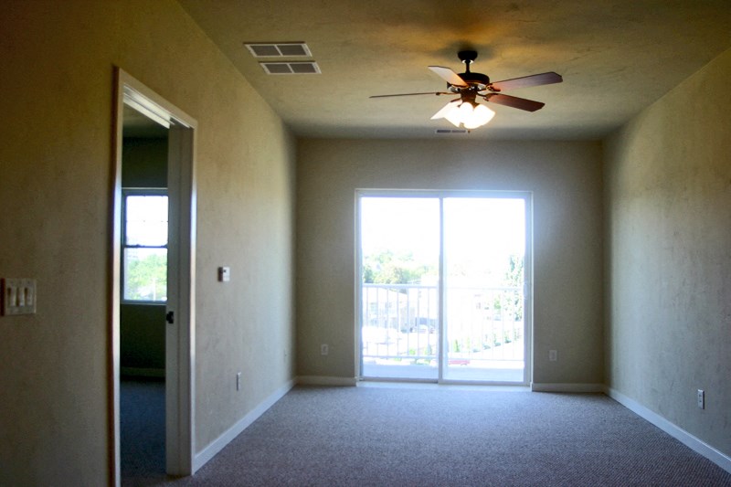 an empty living room with a ceiling fan