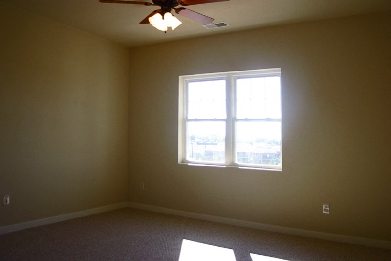 a living room with a window and a ceiling fan