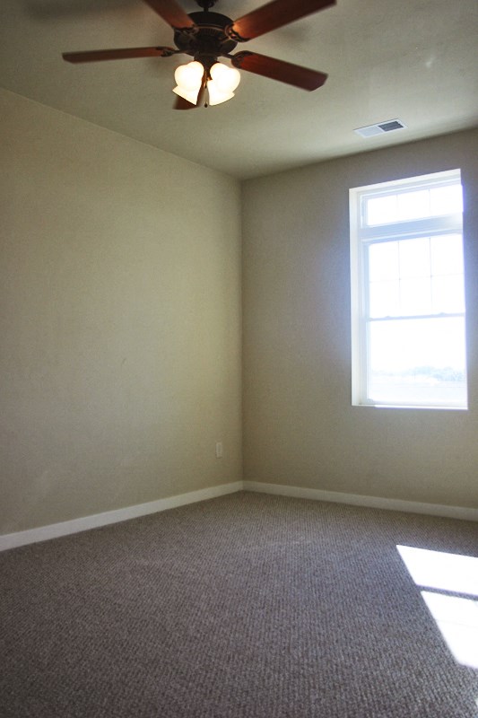 an empty room with a ceiling fan and a window