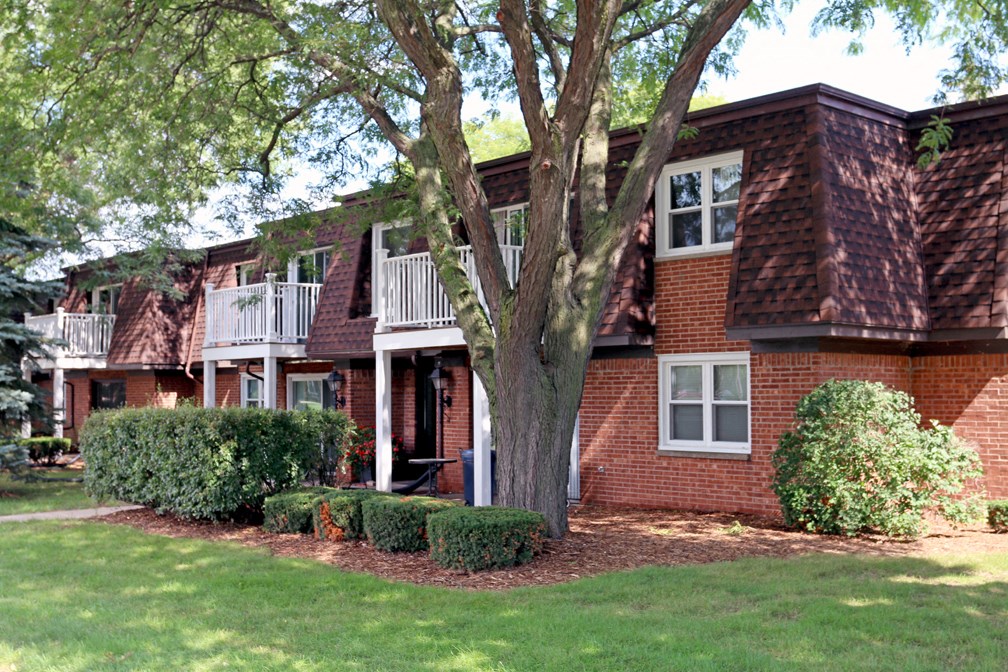 a red brick house with a tree in front of it