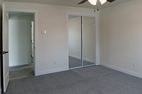 an empty living room with mirrored closet doors