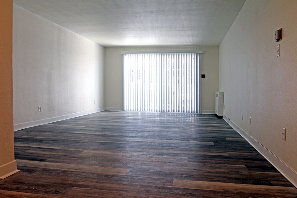 an empty living room with wood floors and a window
