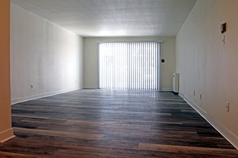 an empty living room with wood floors and a window