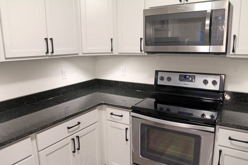 a kitchen with white cabinets and a stove and a microwave
