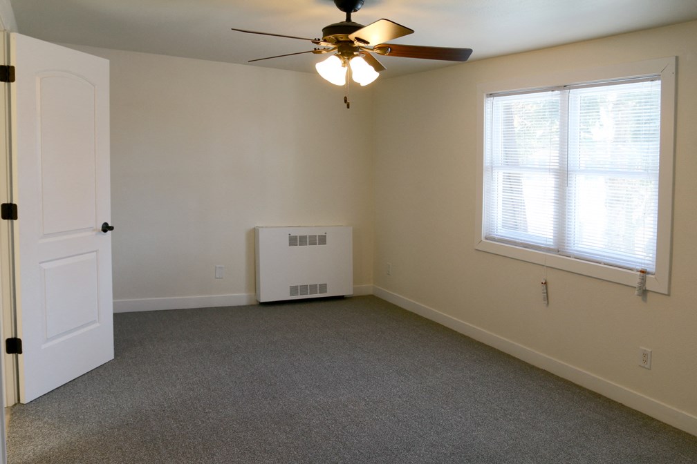 an empty living room with a ceiling fan and a window