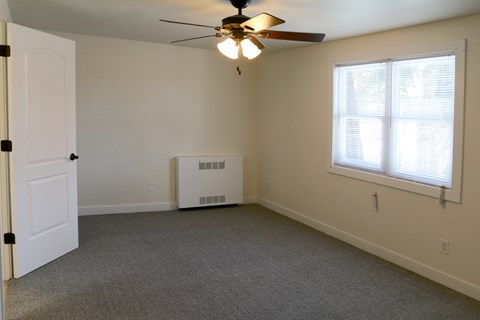 an empty living room with a ceiling fan and a window