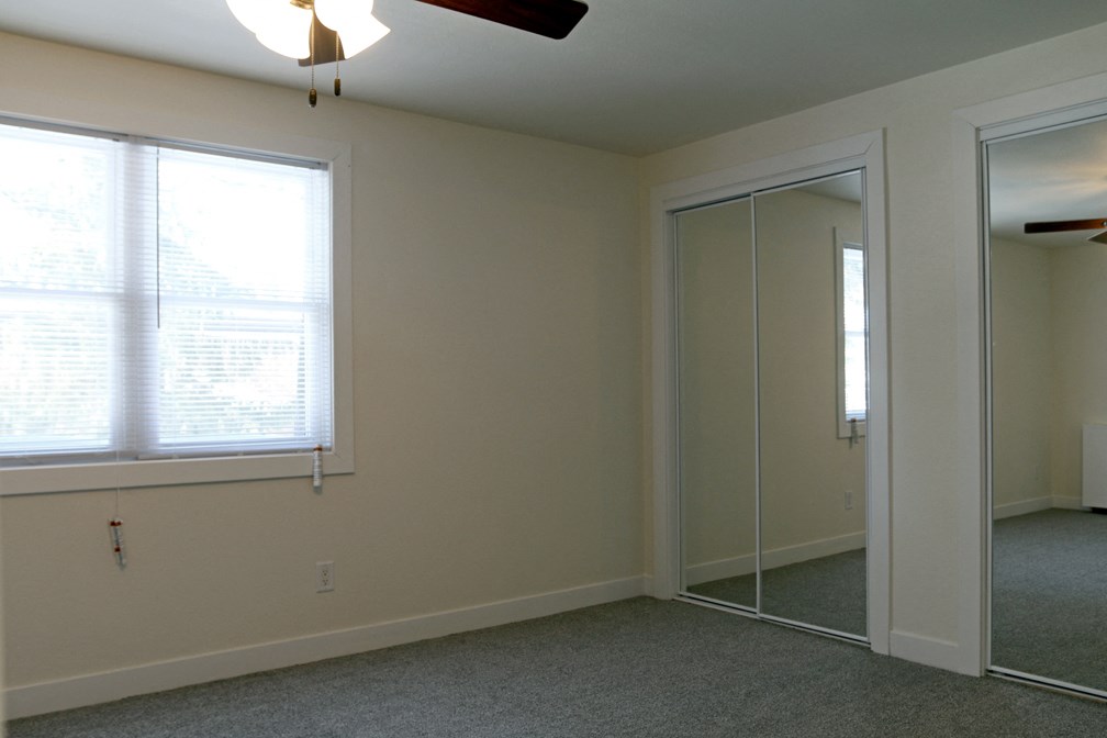 a bedroom with a large window and a mirrored closet