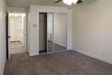 an empty living room with carpet and mirrored closet doors