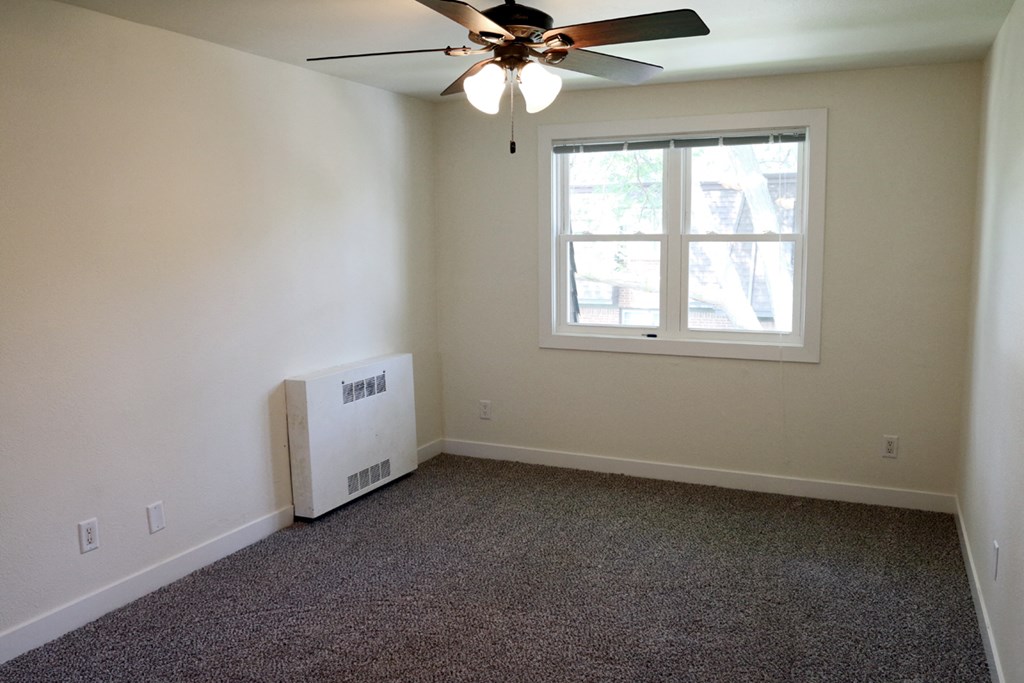 an empty room with a ceiling fan and a window