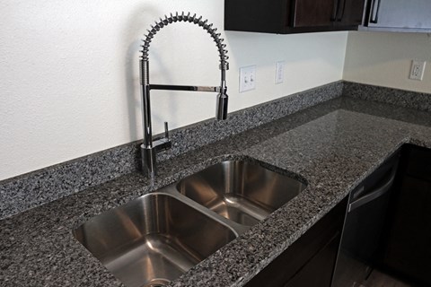 a kitchen sink with a faucet in a granite counter top