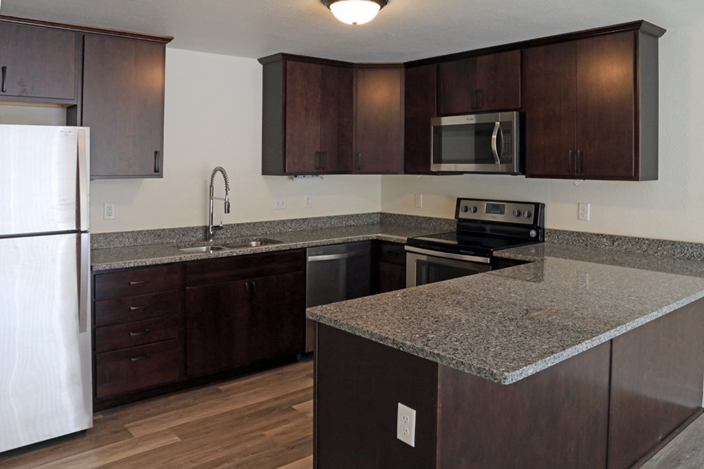 a kitchen with granite counter tops and wooden cabinets