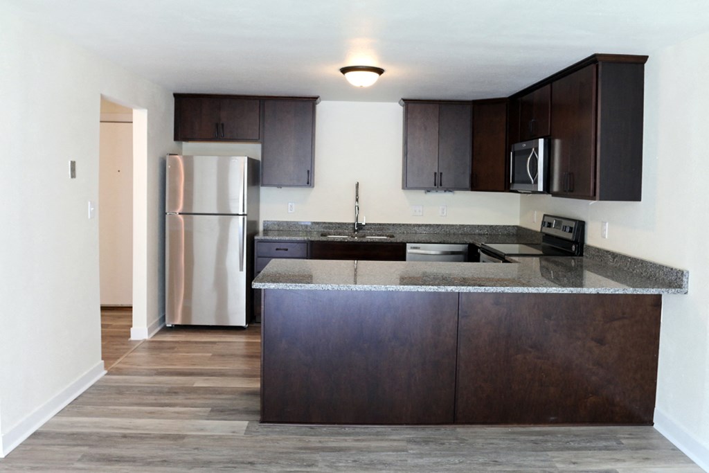 an empty kitchen with stainless steel appliances and wooden cabinets