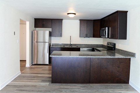 an empty kitchen with stainless steel appliances and wooden cabinets