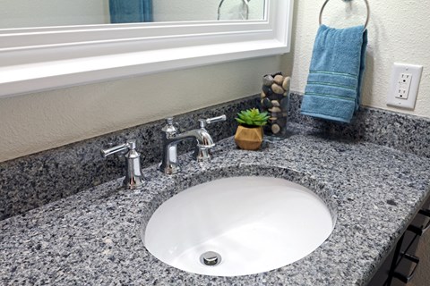 a bathroom sink with granite counter top and a mirror