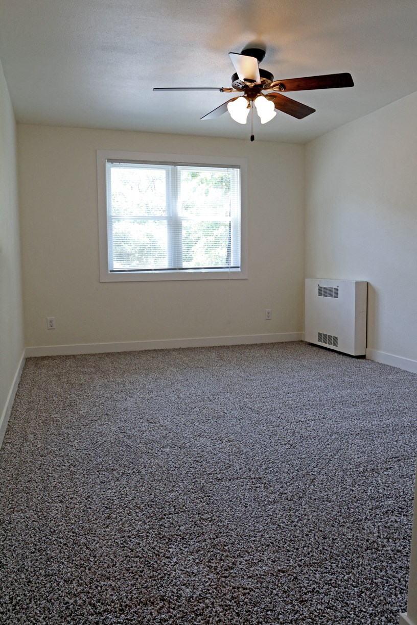 an empty room with a ceiling fan and a window