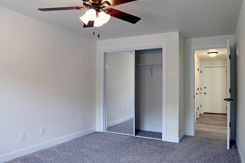 an empty bedroom with a ceiling fan and a closet