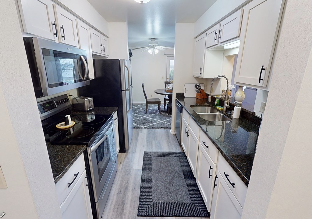 a kitchen with black counter tops and white cabinets