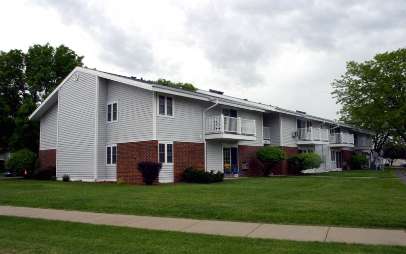 a white apartment building with a green lawn