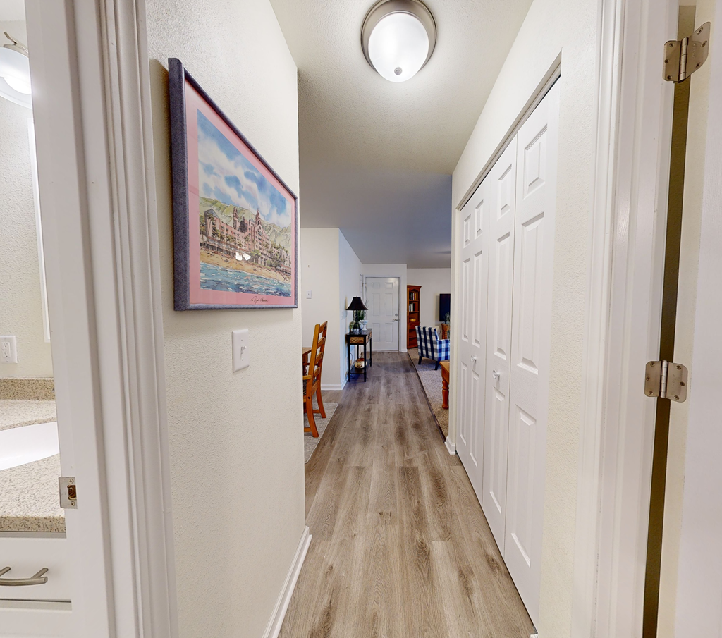 A hallway with a painting on the wall and a chair in the middle.