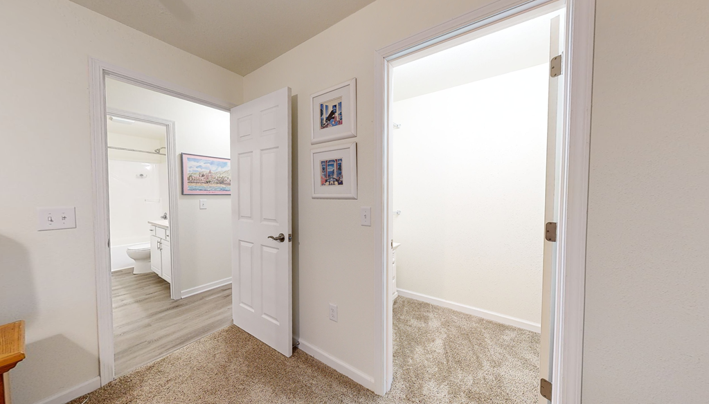 A hallway with a carpeted floor and white walls.