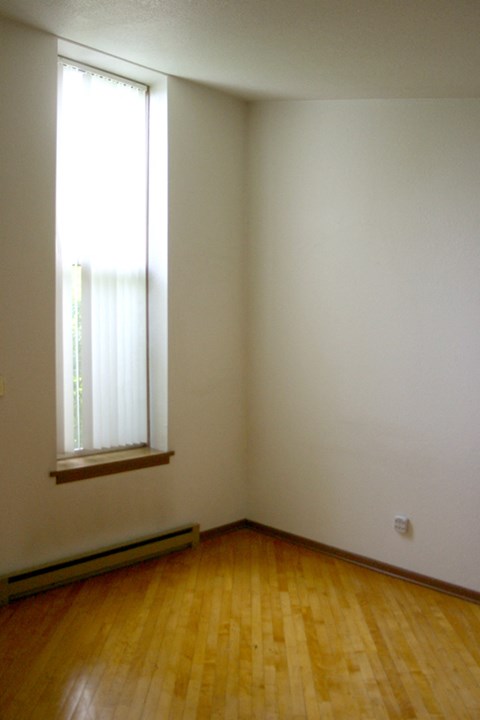 an empty room with a window and wooden floors