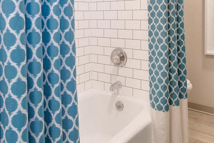 a bathroom with a blue shower curtain and a white tub