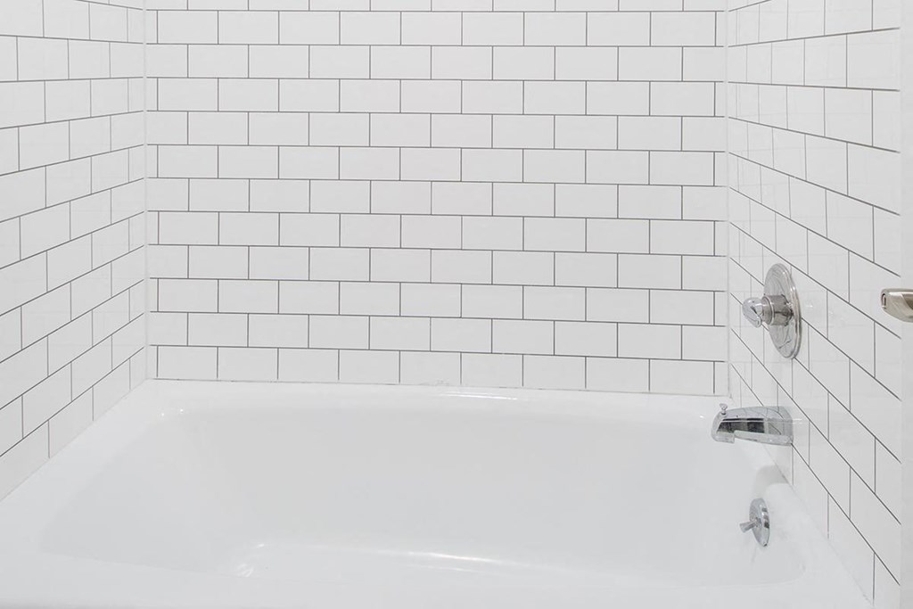 a white bath tub in a white tiled bathroom