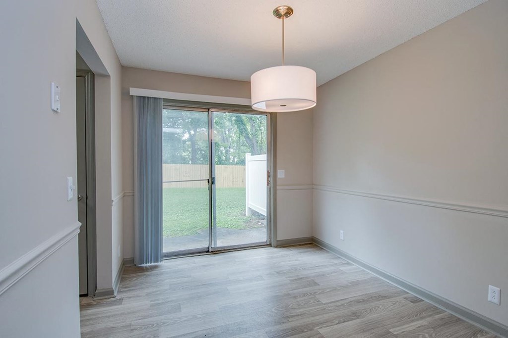 an empty living room with a sliding glass door to a yard