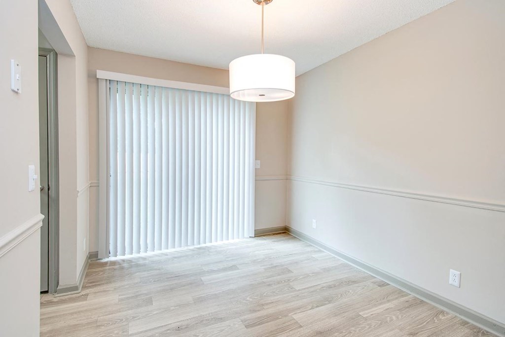 an empty living room with a large window and blinds