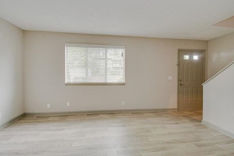 an empty living room with a door and a window