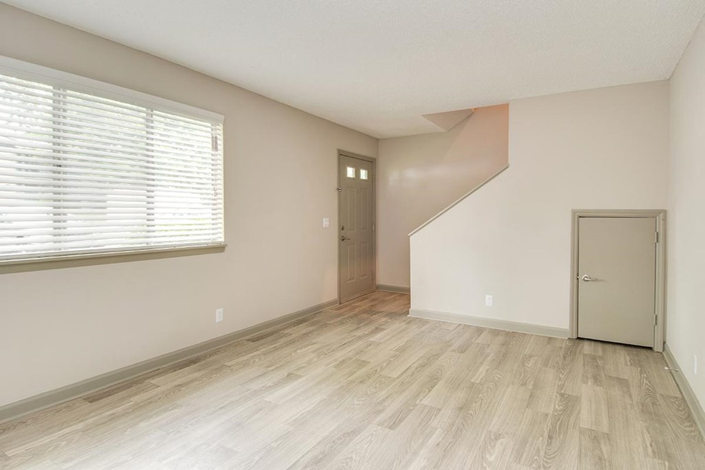 an empty living room with a large window and a door