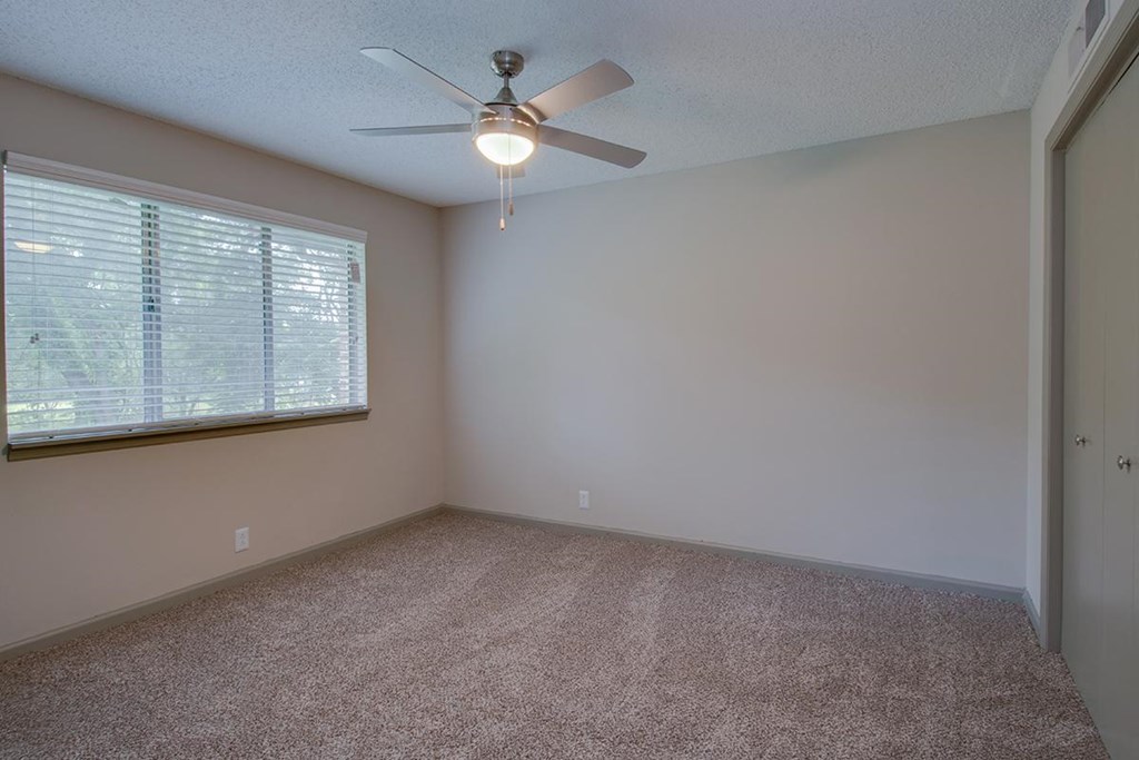 a bedroom with a ceiling fan and a window