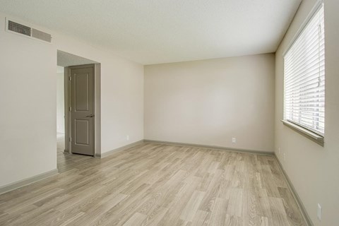 an empty living room with wood flooring and a window