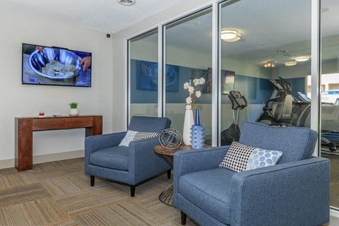 a living room with two blue chairs and a tv