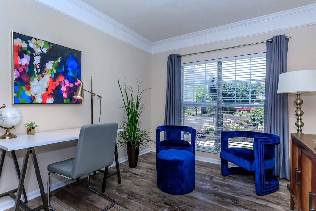 a living room with a desk and chairs and a window