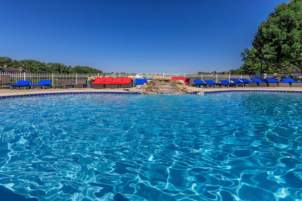 a large swimming pool with blue lounge chairs around it