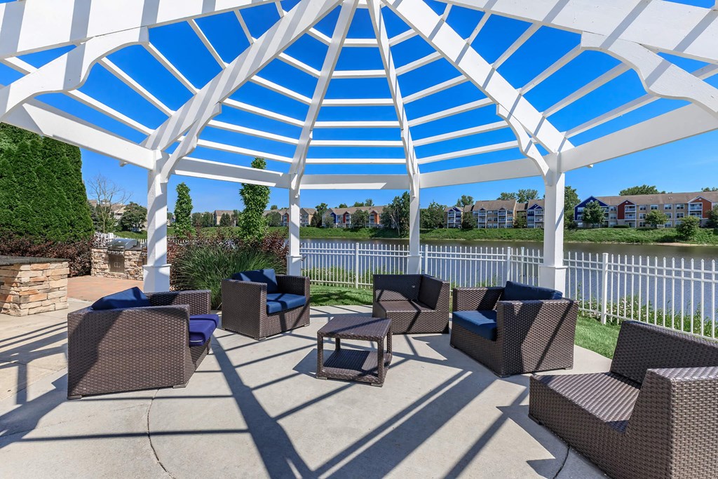 a patio with couches and chairs under a blue and white canopy