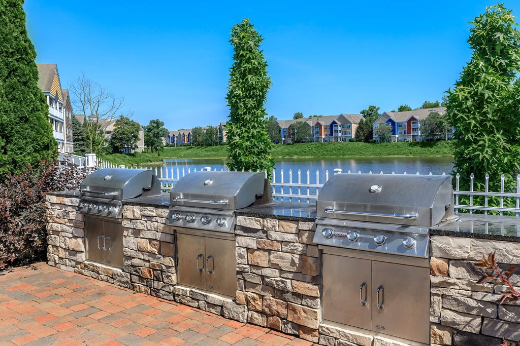 two stainless steel barbecue grills on a stone wall with a lake in the background