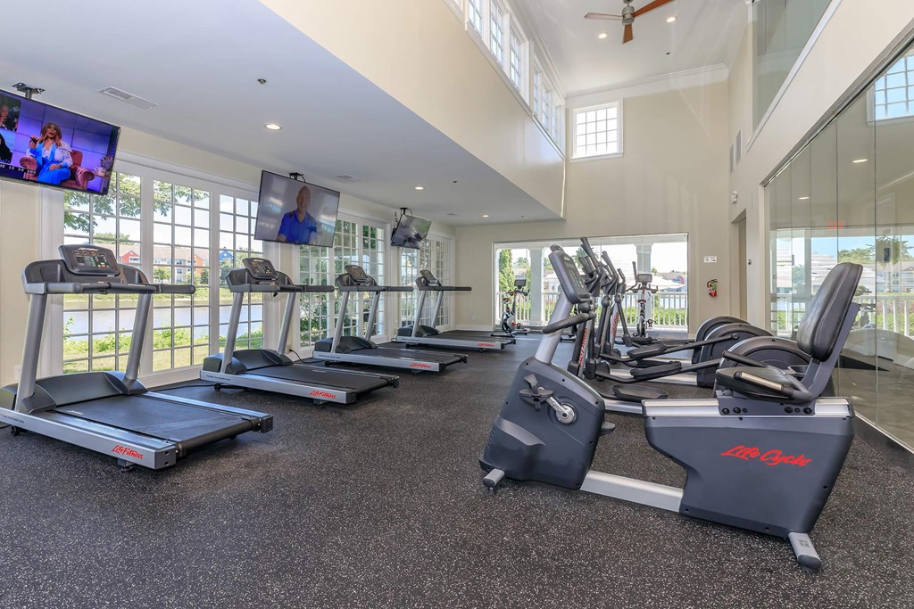a gym with cardio equipment and windows in a building