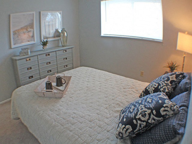 a bedroom with a bed, dresser, and a window  at Valley York Apartments, Parma Heights, 44130
