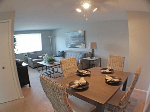 a dining room with a table and chairs and living room in the background  at Valley York Apartments, Ohio