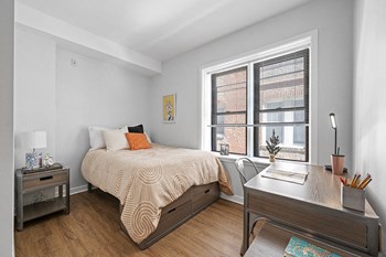 Spacious furnished student apartment bedroom with large windows, vinyl hardwood floors, and white walls - Photo Gallery 8