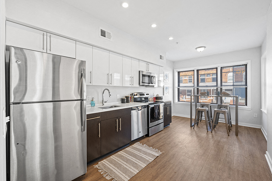 Breakfast nook and large windows in open kitchen with stainless steel appliances and modern cabinetry