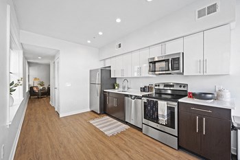 Open kitchen layout with stainless steel appliances and vinyl hardwood floors in student apartment rental - Photo Gallery 4