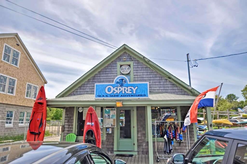 the outside of the odyssey restaurant with flags and cars parked in front of it