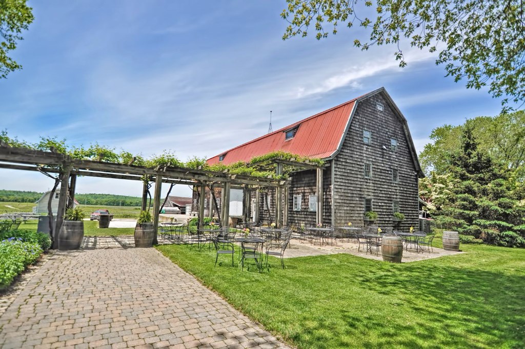 a barn with a red roof and a patio with tables and chairs