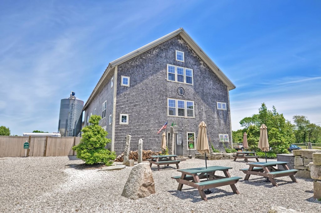 an old barn with a gravel yard with picnic tables