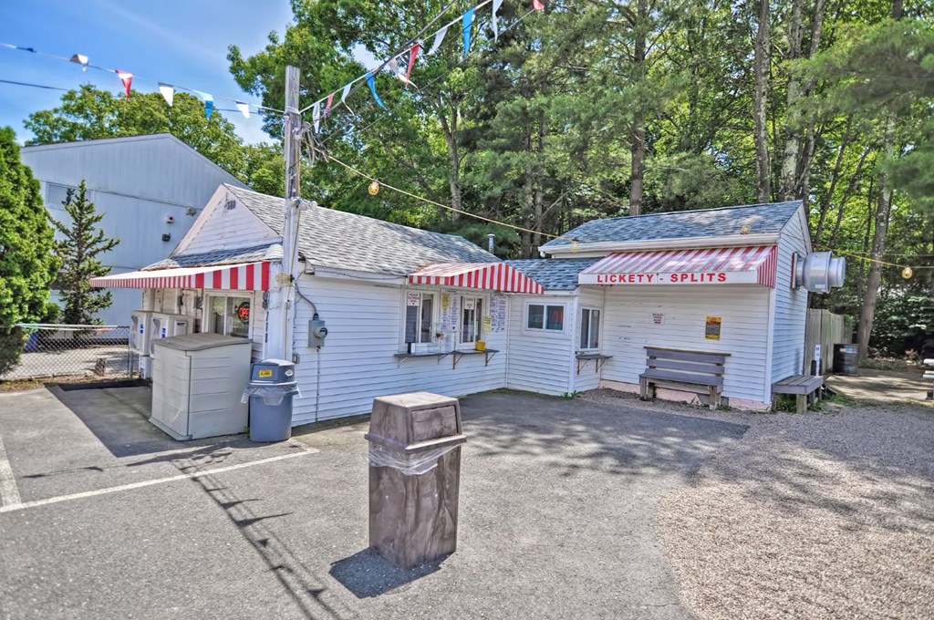 a white chicken shack with a red and white awning and a wooden post