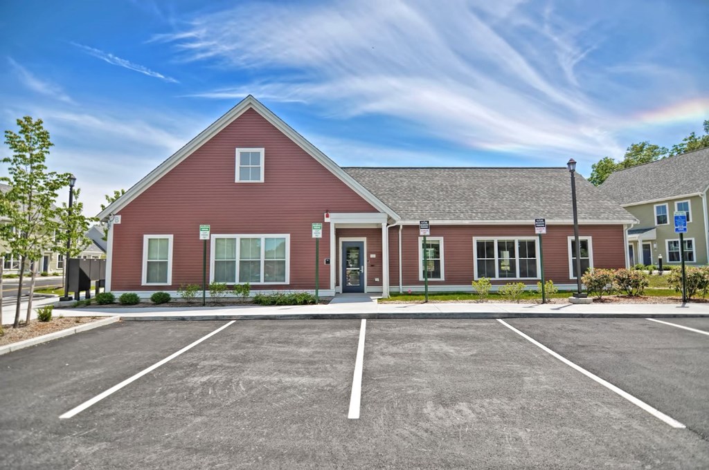 the exterior of a red house with a parking lot
